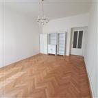 Prostorný obývací pokoj s parketovou podlahou, světlými stěnami a vestavěnými skříněmi, vhodný pro moderní bydlení.